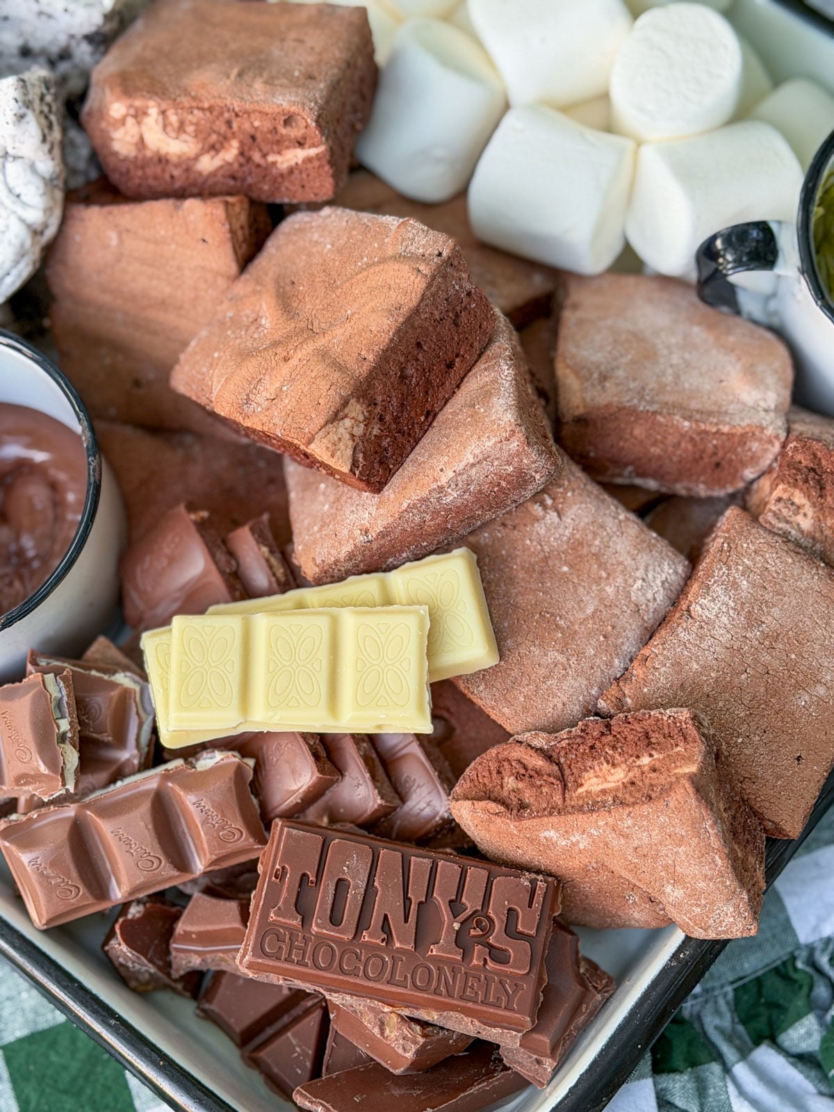 Assorted chocolate bars and marshmallow pieces on a s'mores dessert tray.