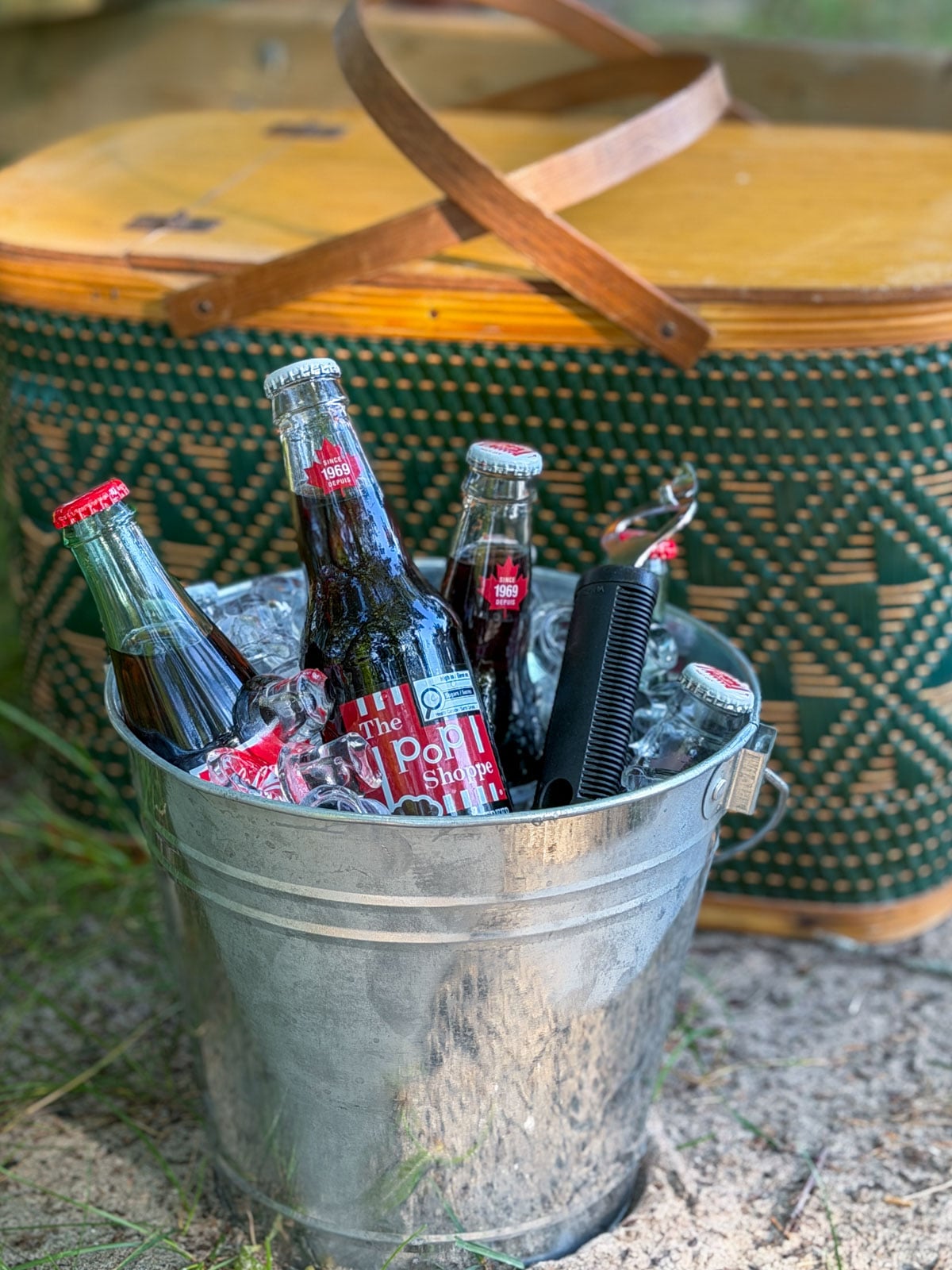 Pop Shoppe glass soda bottles chilling in a galvanized ice bucket with a bottle opener.