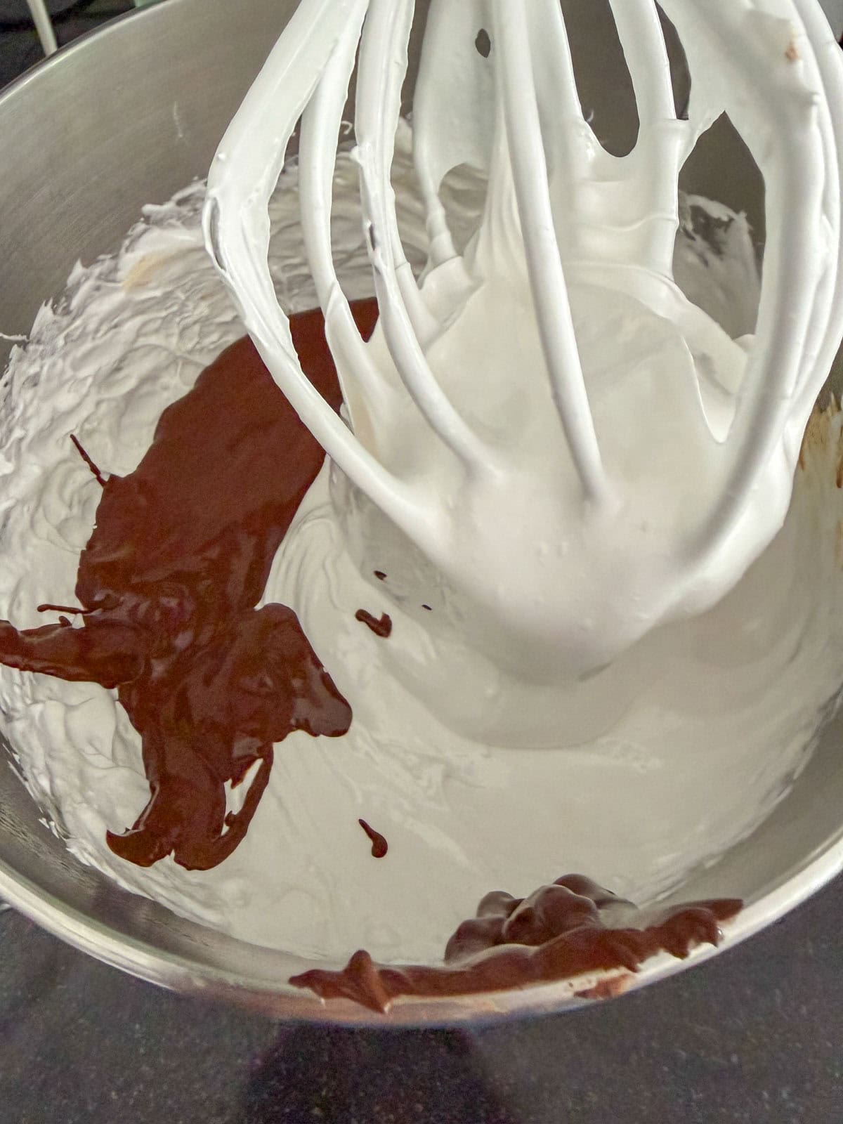 Chocolate cocoa paste being poured into whipped marshmallow.