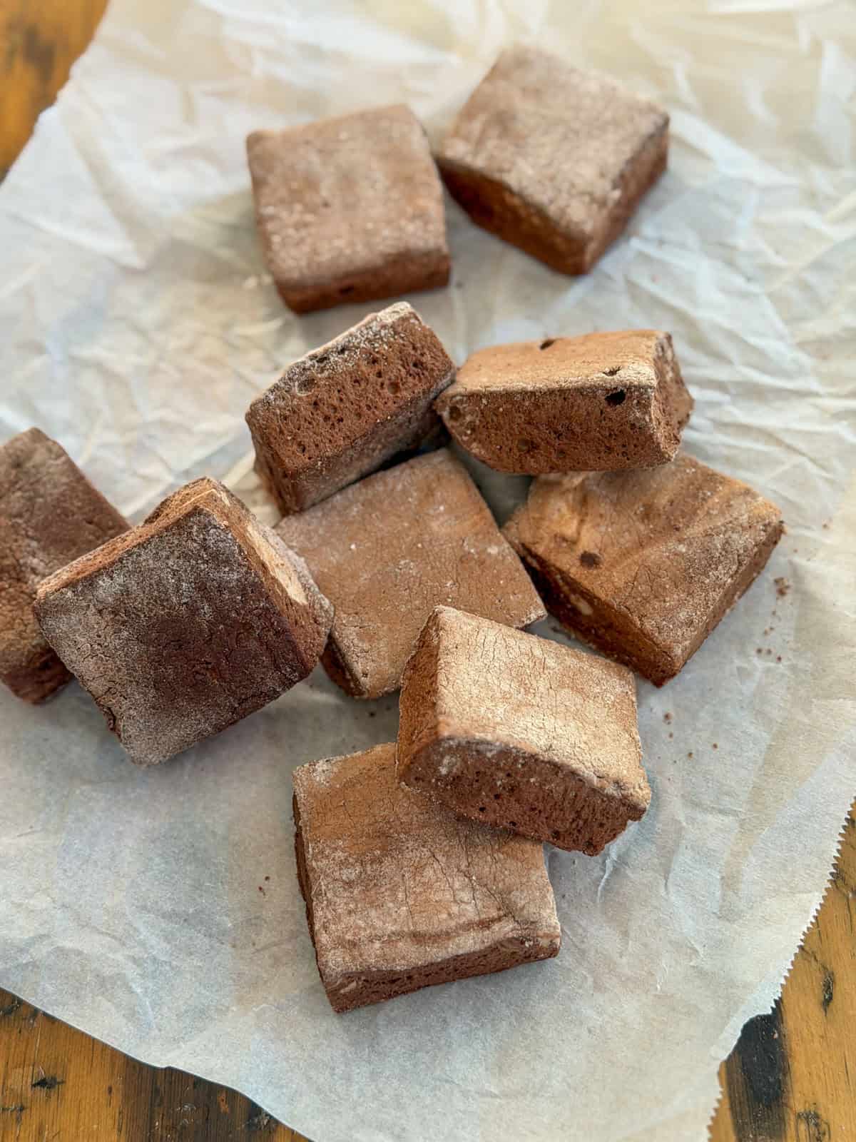 Chocolate marshmallows dusted with cocoa coating on parchment paper.