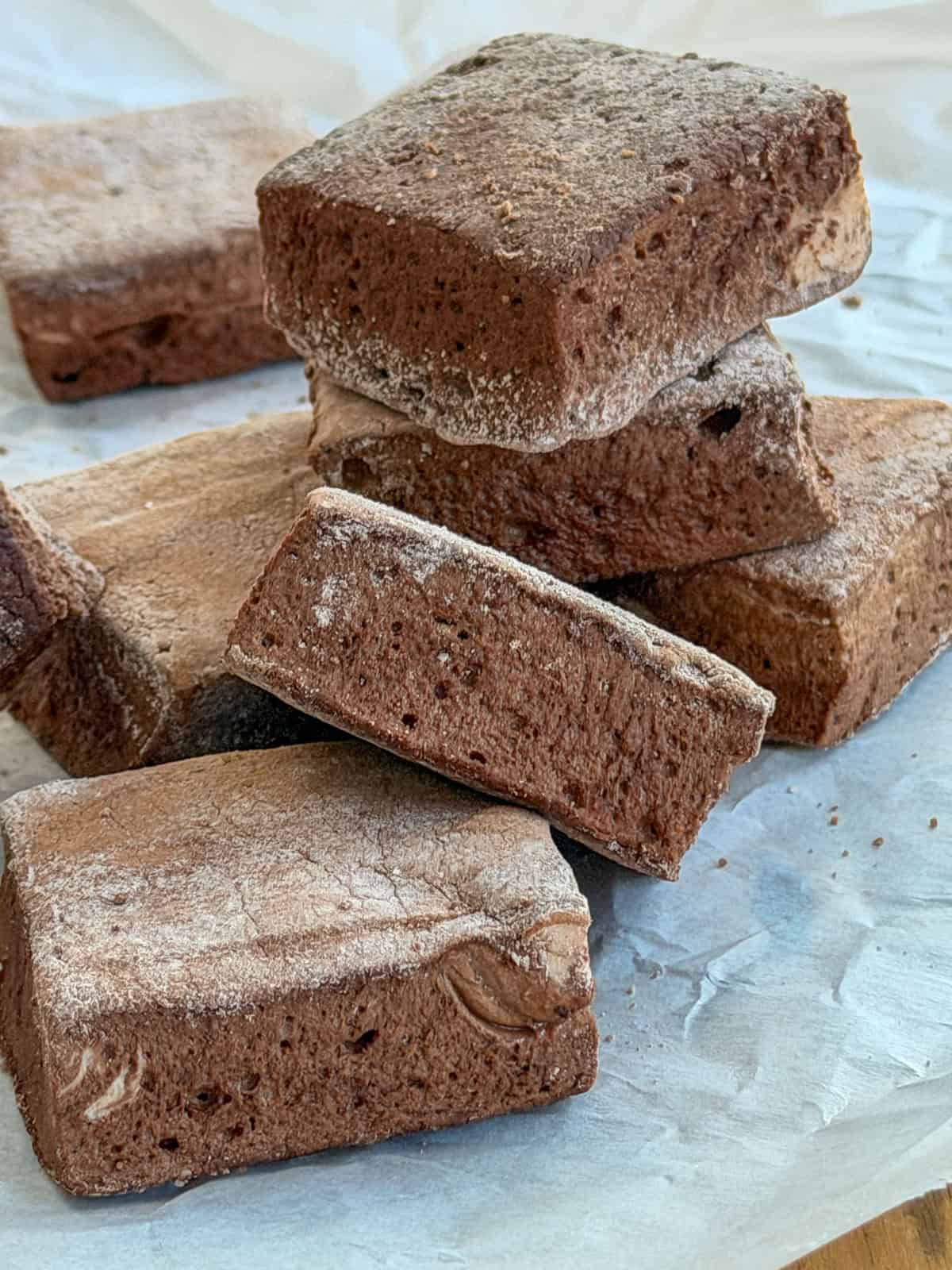 Cut chocolate marshmallows dusted with cocoa on parchment paper.