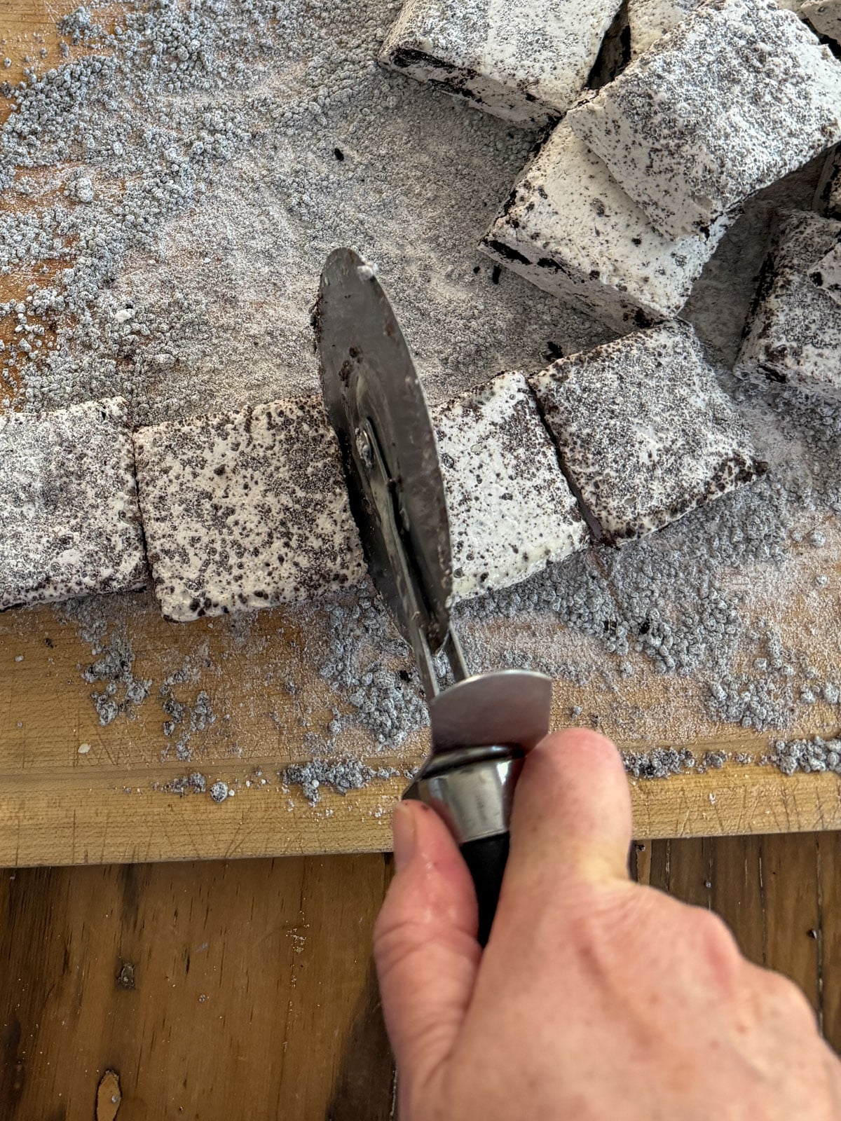 Cutting set Oreo marshmallow into squares with an oiled pizza cutter.