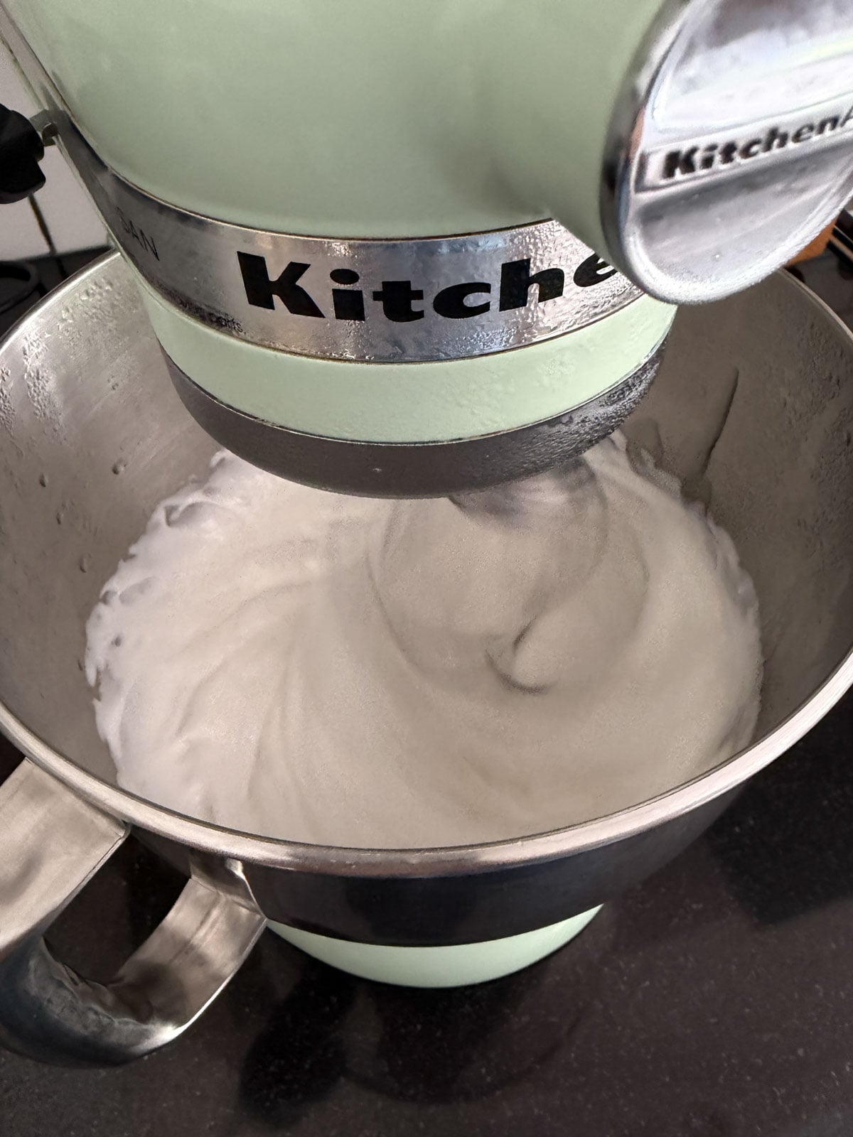 Whipped marshmallow mixture in a stand mixer bowl.