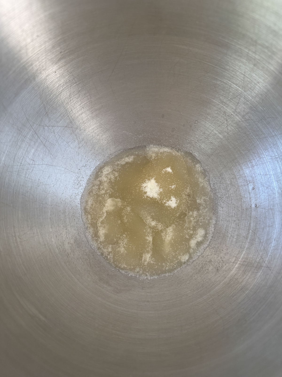 Unflavored gelatin blooming in cold water in a stand mixer bowl.