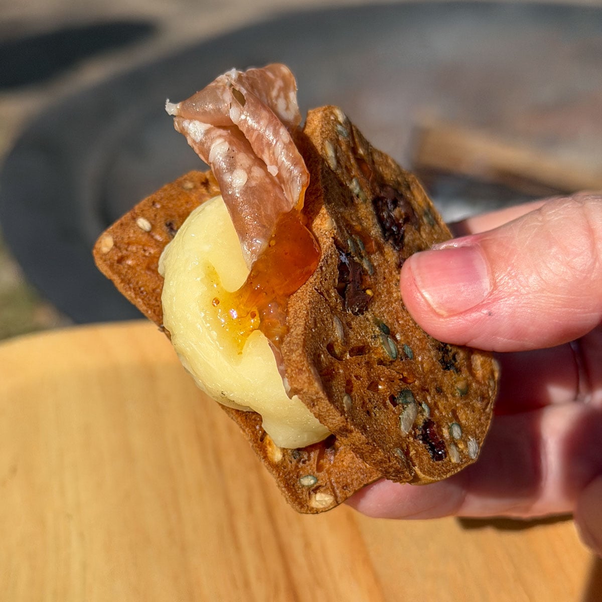 Melted cheddar and apple savory s'more held in hand with hot honey drizzle.