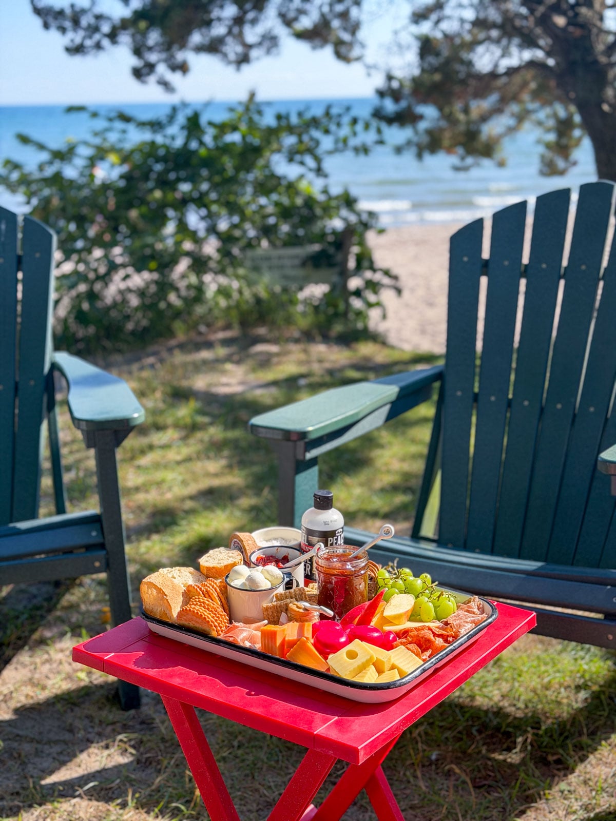 Savory s'mores charcuterie tray set on a red table near the beach.