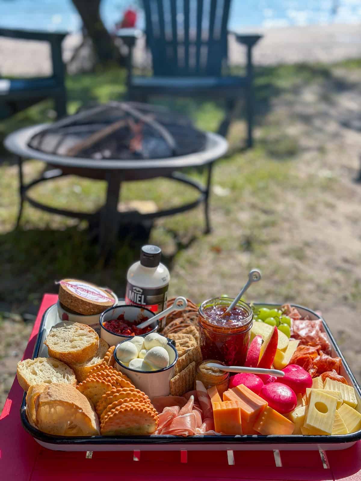 Savory s'mores tray displayed beside a campfire pit at the beach.