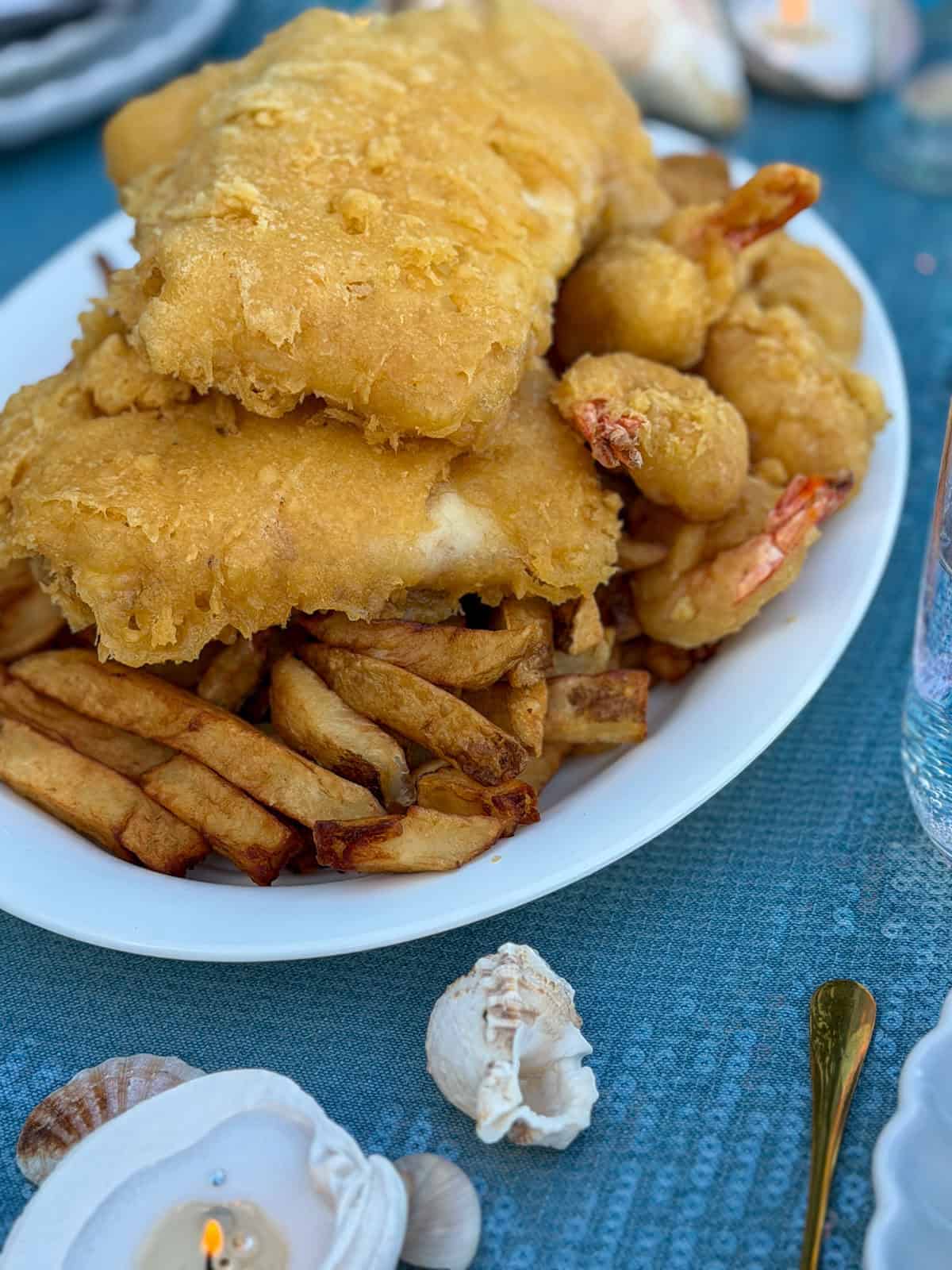 Golden fried fish, shrimp, and chips on a white platter.