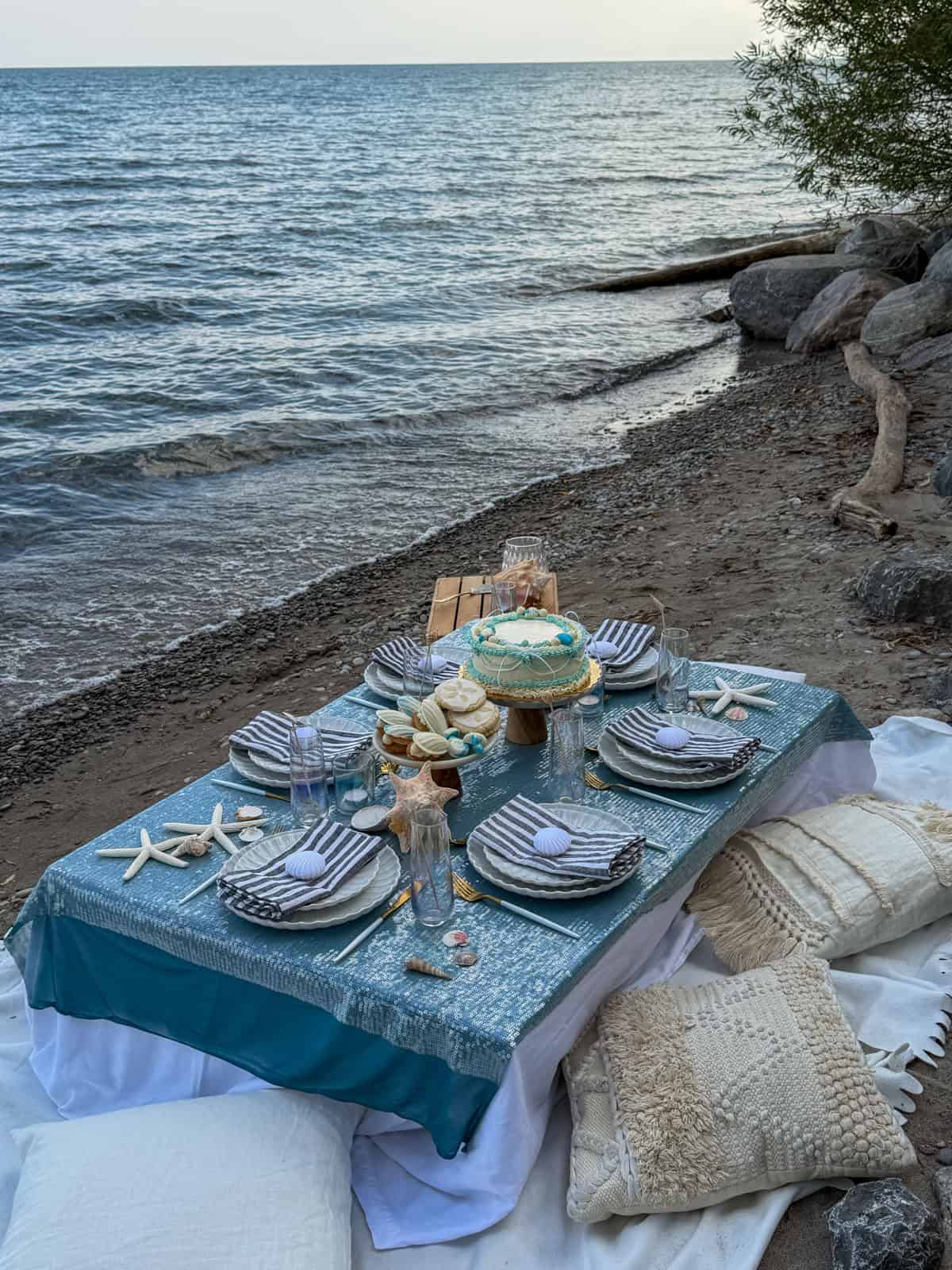Blue sequin table set for an adult mermaid party on the beach.