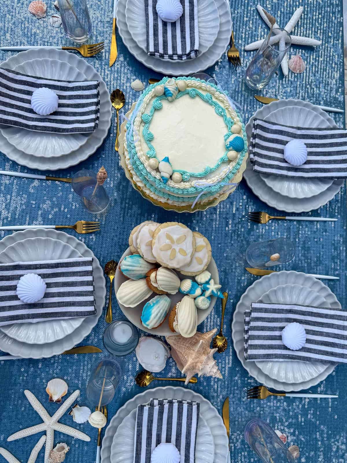 Overhead view of mermaid party table with striped napkins and seashells.