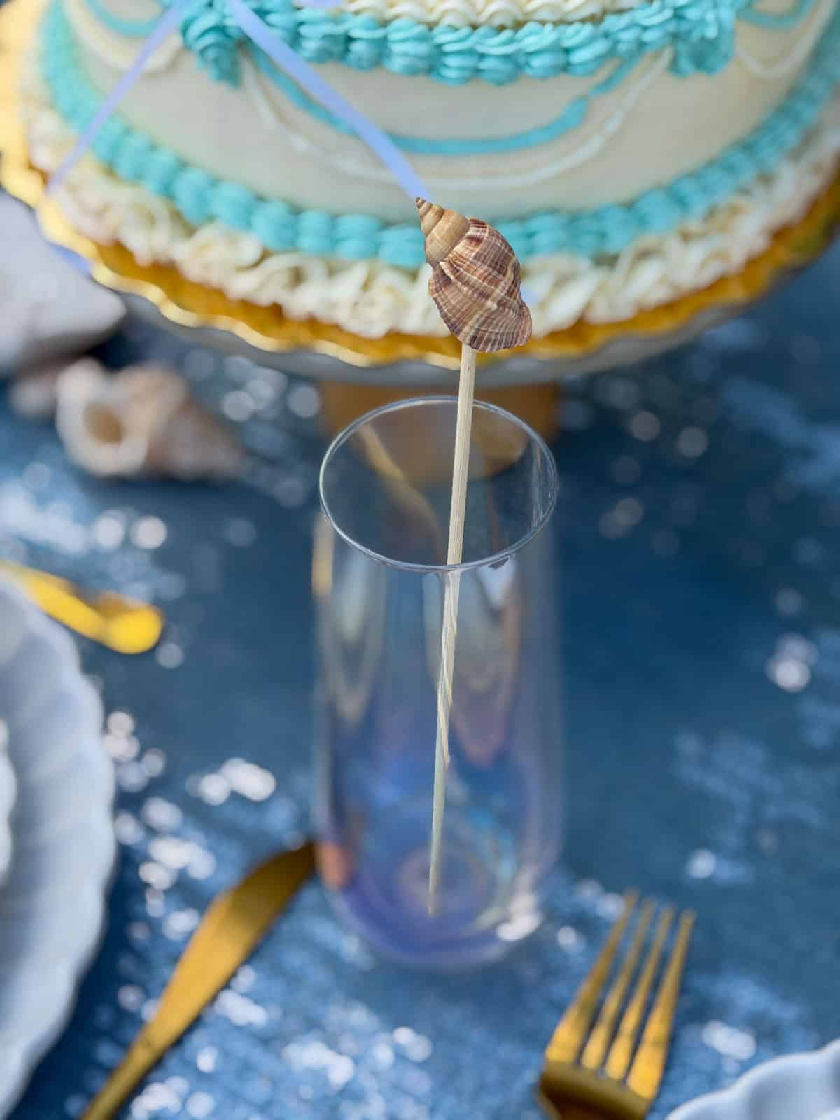 DIY Seashell drink stir stick in an iridescent stemless wine glass.