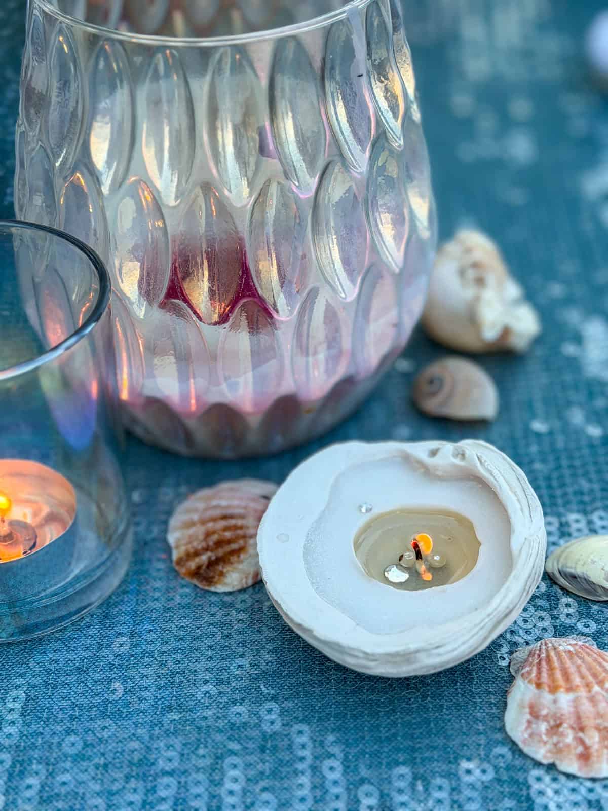 Seashell candles glowing on sequin tablecloth with iridescent glass.