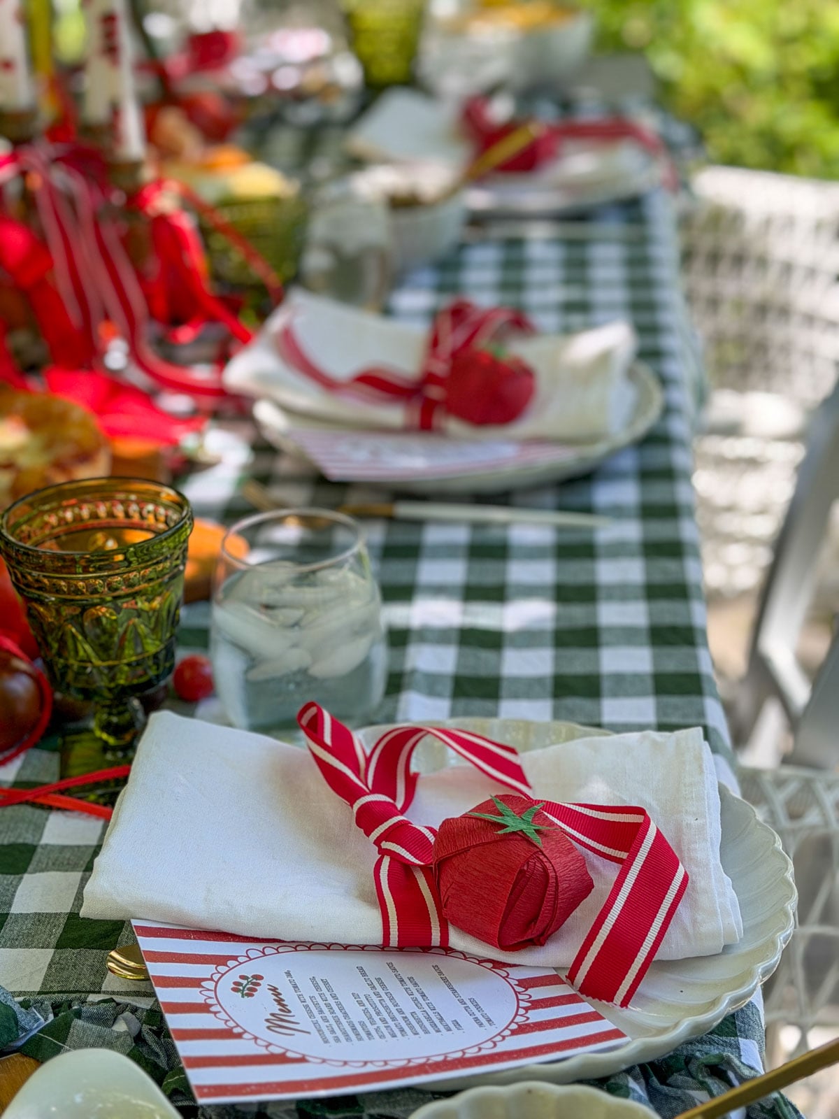 Row of tomato party place settings with red striped napkins.