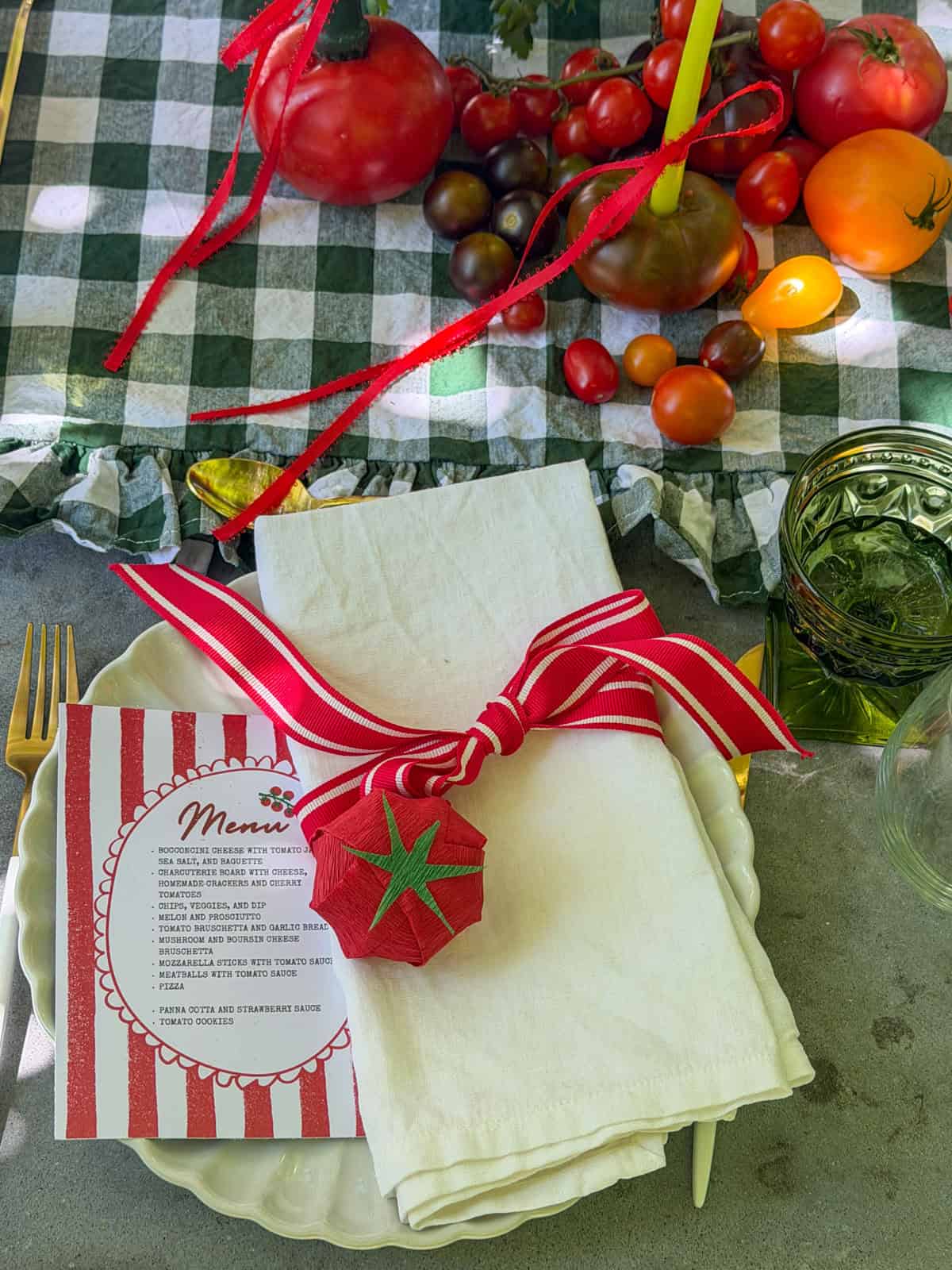 Table setting with striped menu card and tomato party favor.