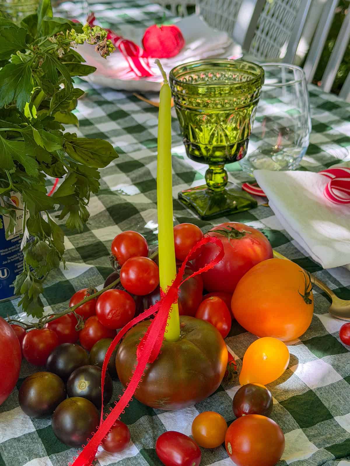 Candle in hollowed tomato surrounded by heirloom tomatoes.