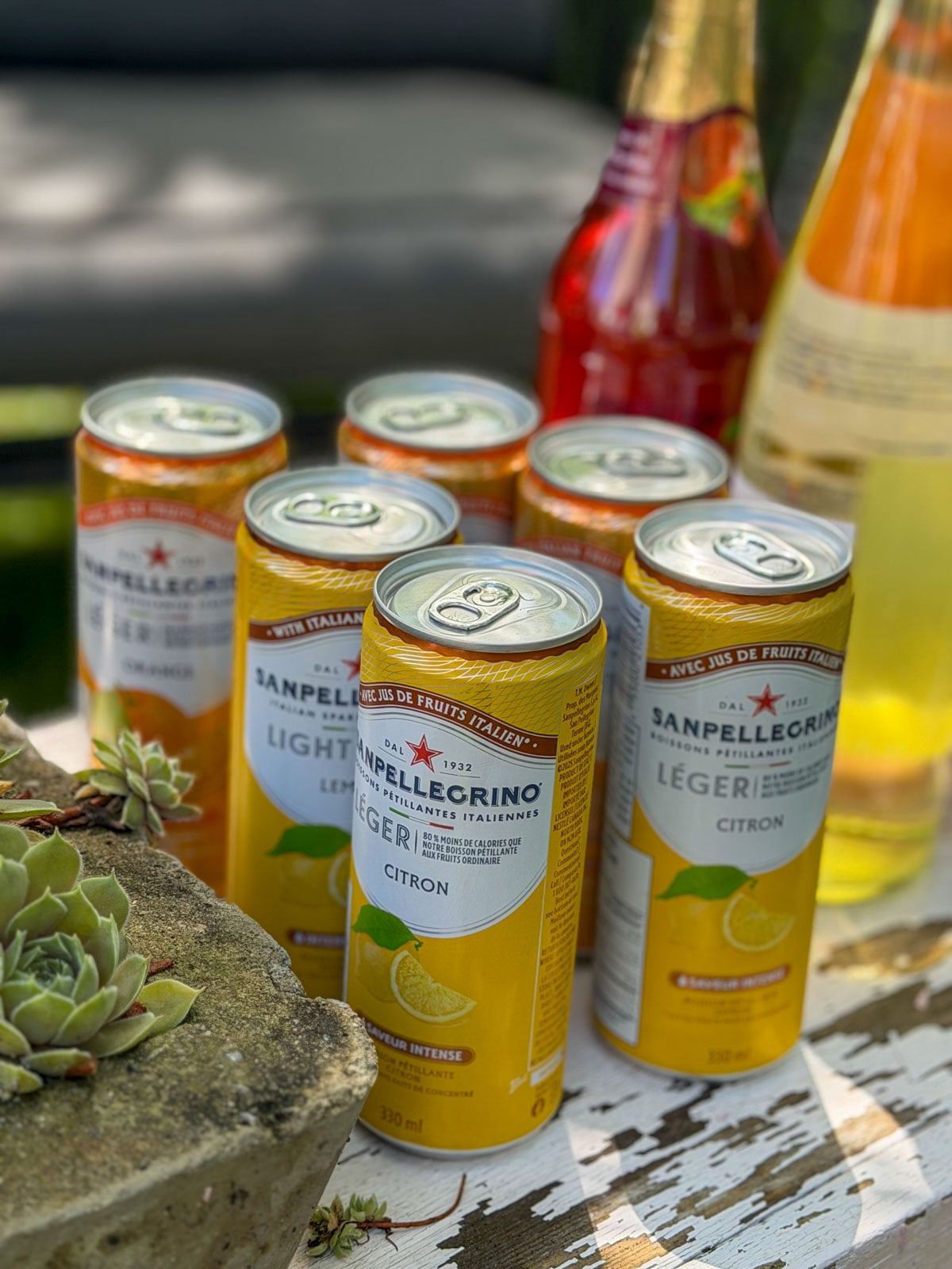 San Pellegrino orange and lemon soda cans and Italian wine bottles.
