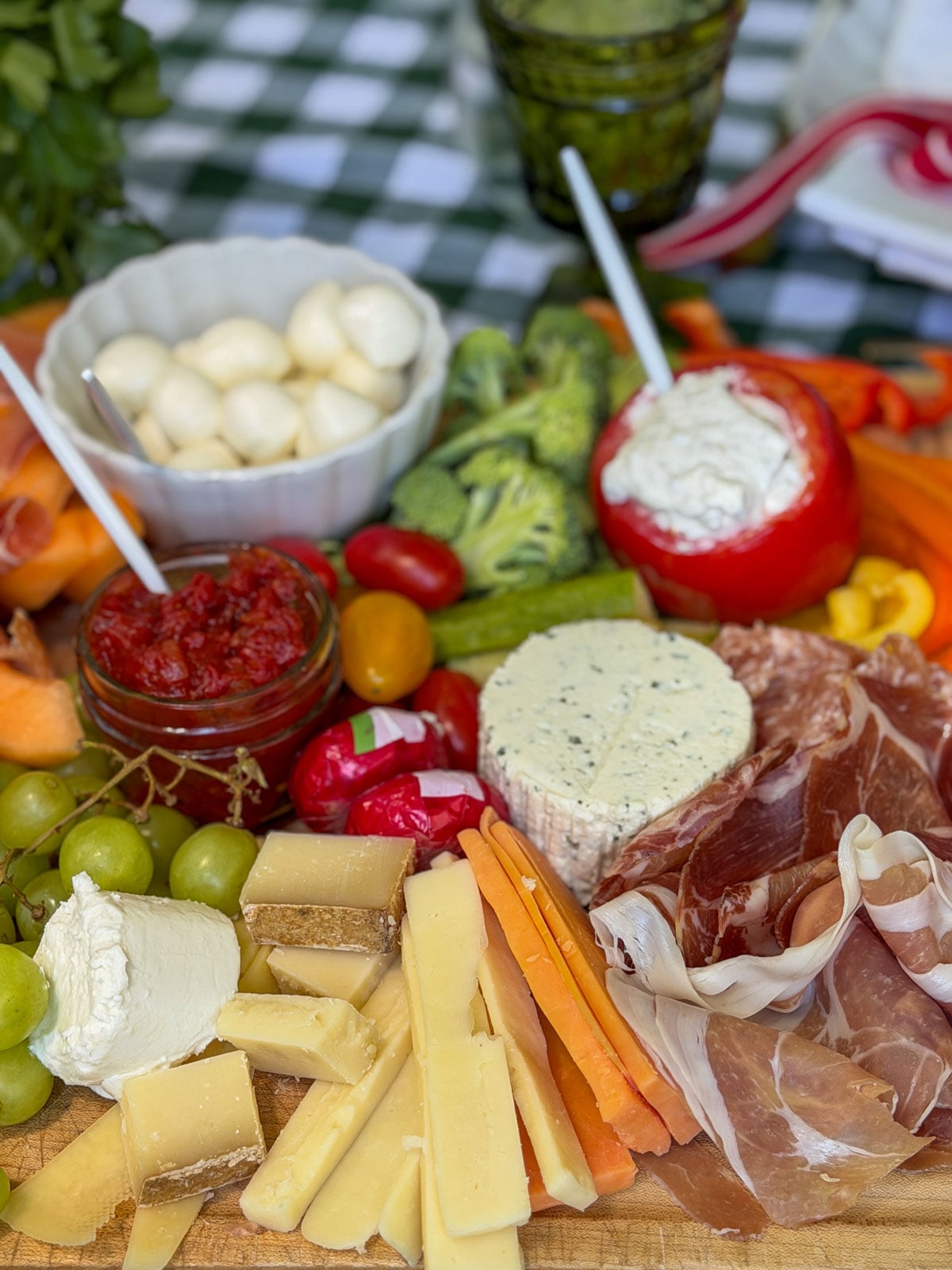 Charcuterie board with cheese, prosciutto, and stuffed tomato dip.