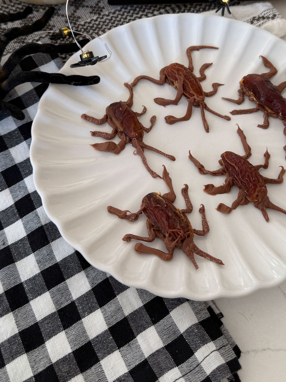 Plate of chocolate peanut butter date cockroaches on a black and white checked napkin.