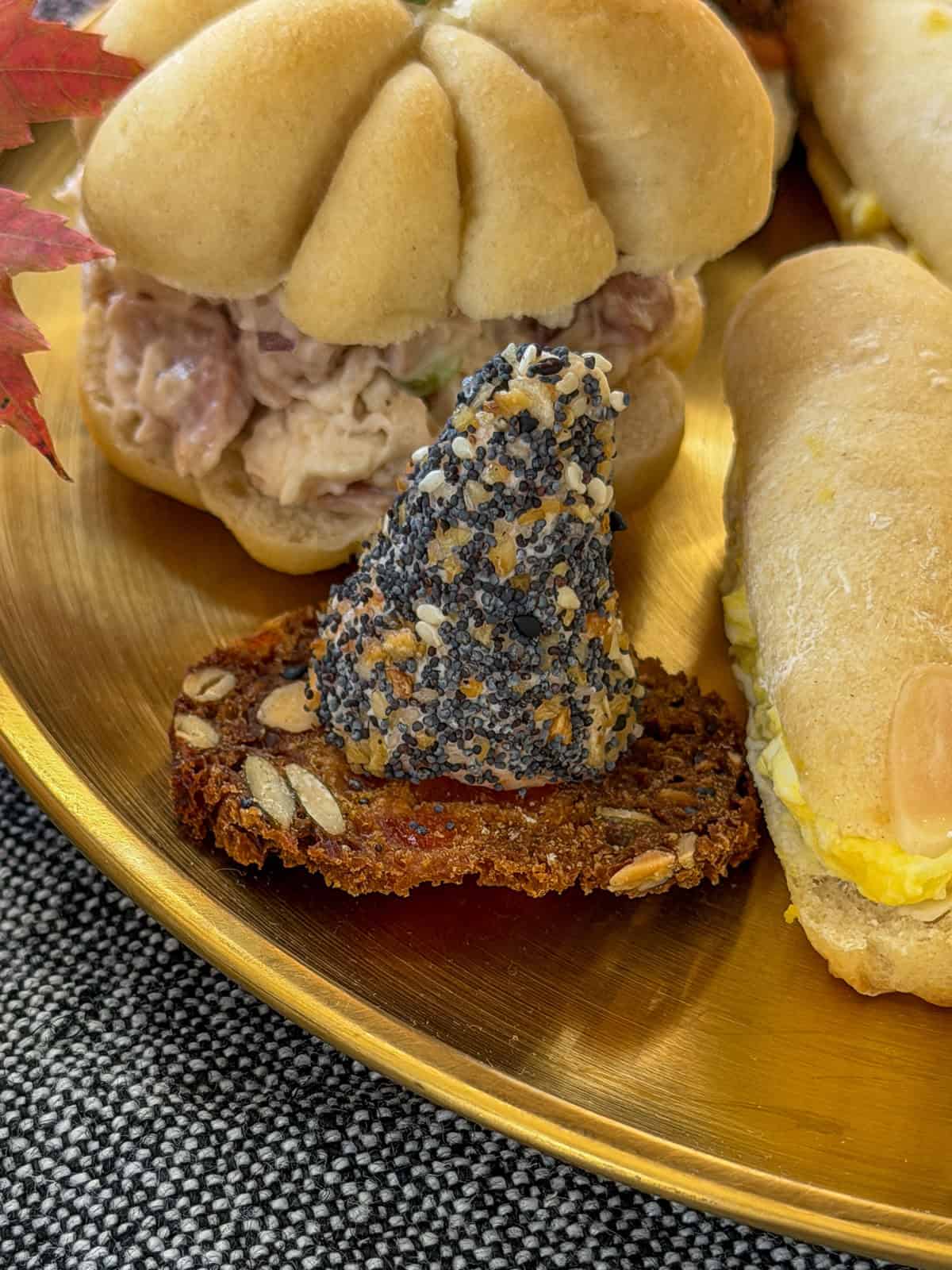 Cone shaped cheeseballs rolled in poppy seeds set on round crackers to look like witch hats.