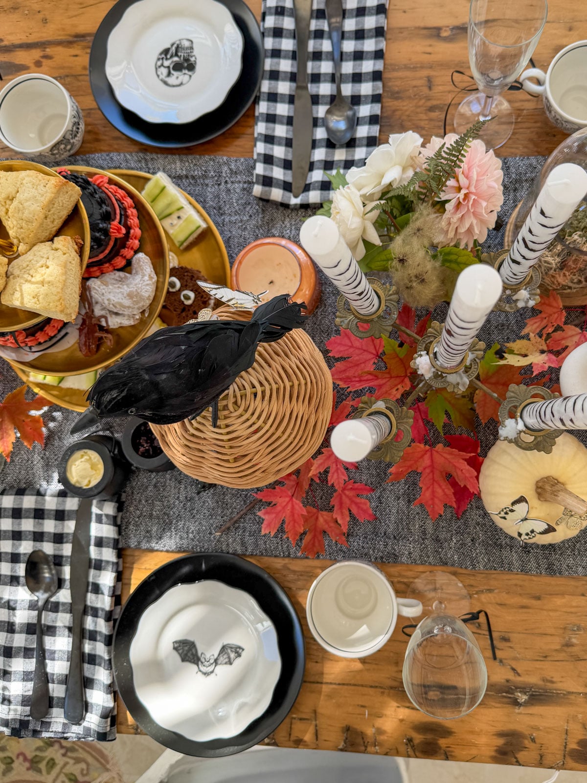Place settings with bat, spider and skull plates on black chargers with black and white checked napkins.